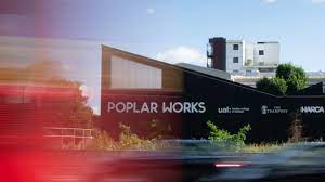 Exterior shot of The Trampery Poplar Works - 384 Abbott Road, Aberfeldy Village, London E14 0UX with London bus driving by creating a red blur