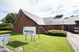 An external shot of Mentec showing a lawned area and some of the car park